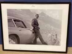 A large photographic print of Sean Connery, leaning against his Aston Martin DB5, screen shot from