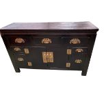 A Chinese cabinet or chest with stylised brass fittings, three short drawers over two cupboard