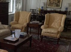 Two traditional winged back arm chairs, upholstered in a gold coloured fabric