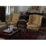 Two traditional winged back arm chairs, upholstered in a gold coloured fabric