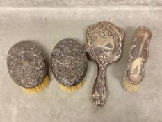 A Sterling silver hand mirror, with Art Nouveau decoration, and three silver mounted brushes of