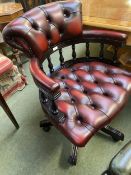 A RED leather and button backed swivel arm chair, with wooden galleried back and five splayed reeded
