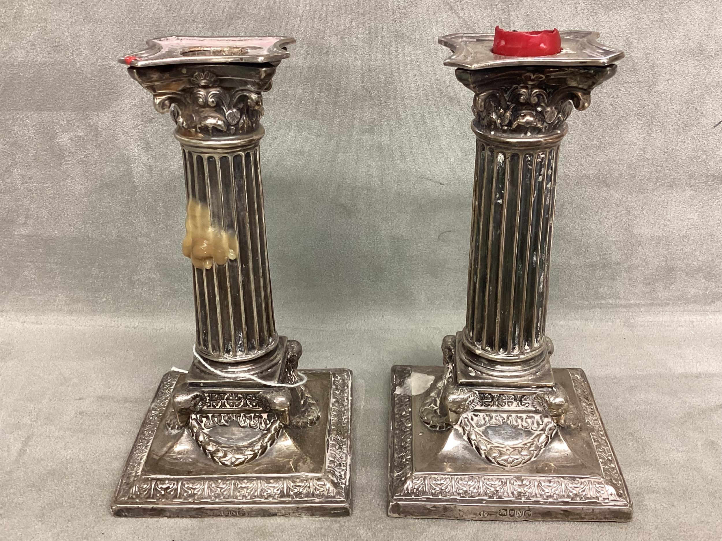 A pair of sterling silver candlesticks, columns and swag decoration on square base by Martin Hall