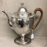 A large Sterling silver coffee pot in The Adams style with fruit wood handle on oval stepped base by