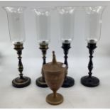 A set of four toleware candlesticks with glass uplighters together with a toleware lidded urn.