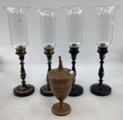 A set of four toleware candlesticks with glass uplighters together with a toleware lidded urn.