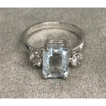 An 18ct white gold aquamarine and diamond ring. Emerald cut aqua with brilliant cut diamond accents.