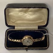 A 9ct gold cased wrist watch on a yellow metal strap. 24mm case.