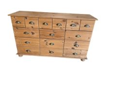 A pine sideboard with 15 small drawers and cup handles. Missing two back bun feet