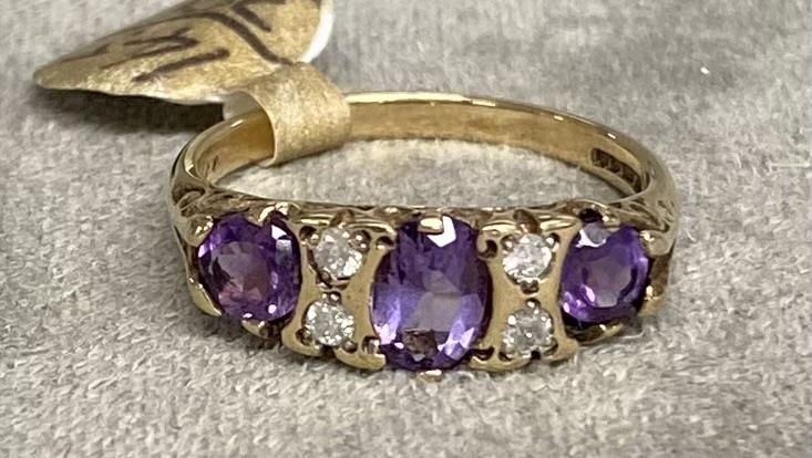 A 9ct gold amethyst and diamond ring. Three free cut amethysts with double brilliant cut diamond