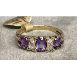 A 9ct gold amethyst and diamond ring. Three free cut amethysts with double brilliant cut diamond