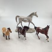 A collection of four Beswick horses. Largest. 30cm x 32cm. Grey, Dunn, Glazed Bay, Unglazed Bay