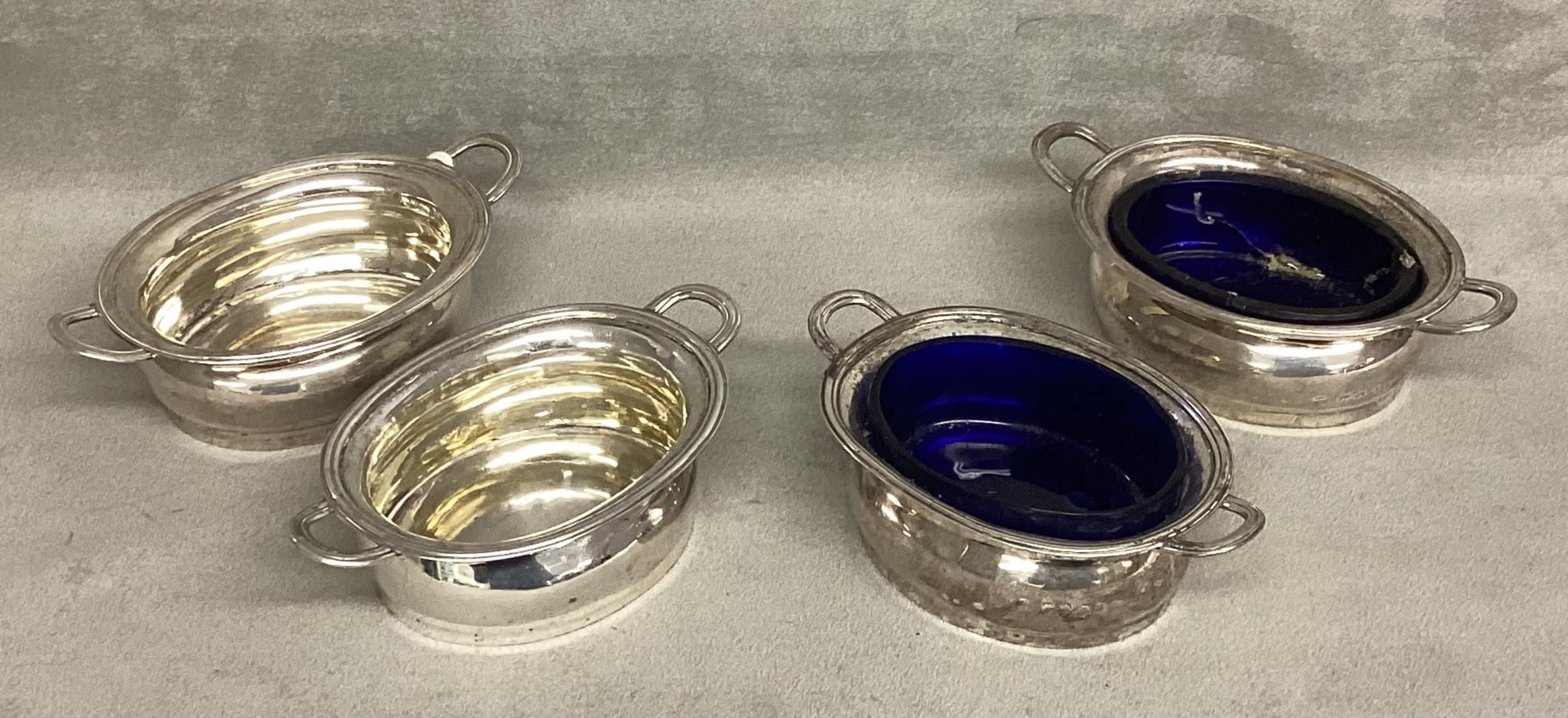 A set of four sterling silver salts, two with blue glass liners. Various dates and makers Silver