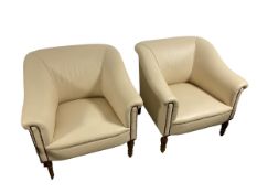 A pair of GEORGE SMITH cream leather arm chairs with brass studded arms, and raised on wooden turned