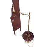 A brass standard lamp, with hinged arm and circular mahogany book rest