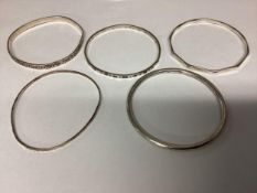A collection of five bangles, four sterling silver and one unmarked white metal. 54g