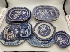 A large collection of blue and white/ willow pattern meat plates , tureen covers etc.