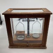 An early 20th century pair of chemists scales with boxed associated weights in an oak and glass