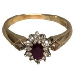 A 9ct gold ruby and diamond ring. Central oval free cut ruby with a surround of single cut diamonds.
