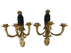 A pair of classical gilded three branch carved wooden wall sconces, with carved faces in the style