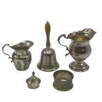 A collection of Sterling Silver items, two cream jugs, a bell and a napkin ring, Various dates and
