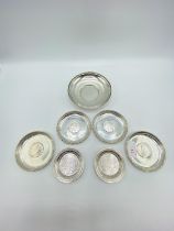 A set of 4 silver coin set pin dishes and a sterling silver example and 2 unmarked white metal