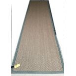 A Sisal Runner rug, 488 x 121cm, with green material edging