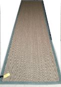 A Sisal Runner rug, 488 x 121cm, with green material edging