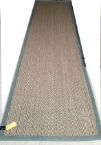 A Sisal Runner rug, 488 x 121cm, with green material edging