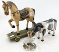 A carved model of a cow, a painted horse on wheels and a ceramic sheep posy vase