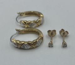 A pair of diamond ear studs together with a pair of yellow metal hoop earrings.