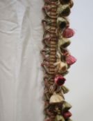 A pair of cream silk curtains, edged with a brocade of cream, olive green and burgundy tassels