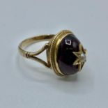 A Victorian unmarked yellow metal garnet and seed pearl dress ring, oval cabochon garnet with star
