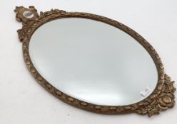 A gilt framed oval mirror, topped by inset ceramic oval panel, bevelled plate, 43-78cm