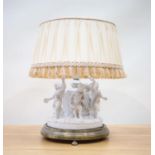A Louis XV porcelain and brass mounted table lamp, decorated dancing cherubs, and a cream pleated