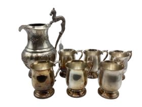 A collection of 6 silver plated mugs together with a silver plated water jug with embossed