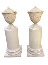 Pair of composite lidded urns with satyr masks on composite half column plinths / stands . Urns 46