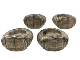 Four middle eastern ornamental slave bangles with chased and beadwork decoration