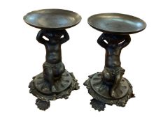 A pair of bronze candlestands, seated putto on circular stylised bases 15 cm H