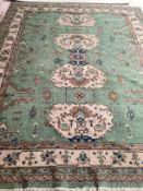 A Turkish style wool rug, central cream medalion on green ground with floral and geometric borders