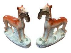 A pair of Staffordshire grey hounds, each with hares in mouth, each 28cm high approx, some wear