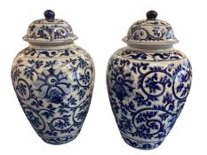 A decorative pair of blue and white ginger jars and covers, with all over large scrolling foliage