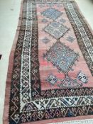 A large Kilim style rug , 3 central geometric diamonds, on a faded teracotta ground, 184cm x 410cm