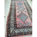 A large Kilim style rug , 3 central geometric diamonds, on a faded teracotta ground, 184cm x 410cm