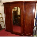 A mid-Victorian mahogany round cornered triple wardrobe, having central mirrored door flanked by