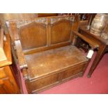 An early 20th century joined oak two-seater twin-panelled monks bench, having fold-over top above