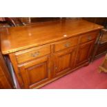 A contemporary joined oak sideboard, the three frieze drawers over conforming recessed panelled