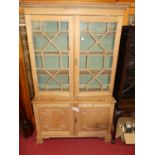 A 19th century pine bookcase cupboard, having twin door astragal glazed upper section over base