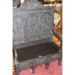 An ebonised, joined, and relief carved oak three-panelled settle, having three short lower