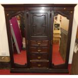 An Edwardian mahogany triple wardrobe, having outer bevelled mirror doors with central upper